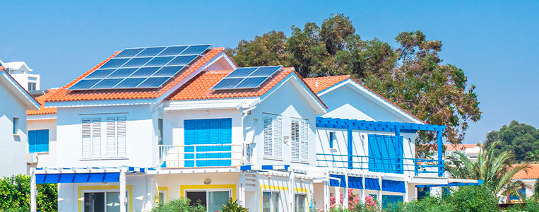Casa branca na praia com painéis solares no telhado.