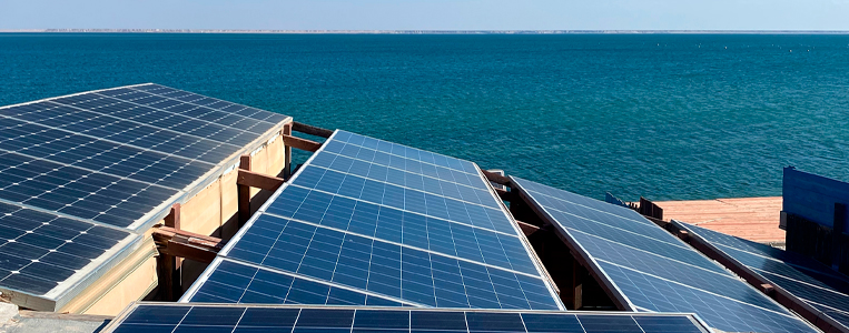 Painéis solares no telhado de uma casa de frente para o mar.