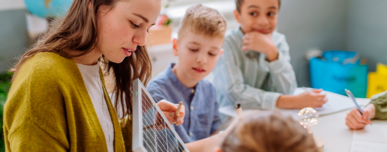 Professora mostrando um painel solar para crianças.