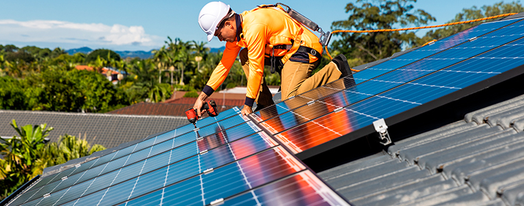 Integrador instalando painéis solares em um telhado.