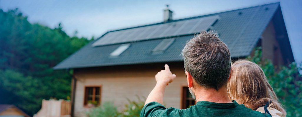 Casal em frente a casa com painéis solares.