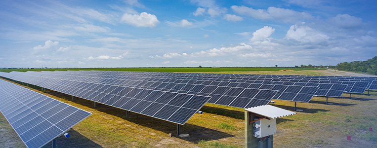 Instalações de painéis solares de energia solar em campo aberto sob céu azul com nuvens, promovendo energia renovável e sustentável.