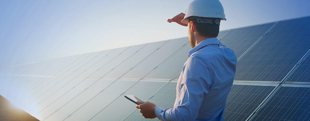 Engenheiro visualizando painel de energia solar ao pôr do sol