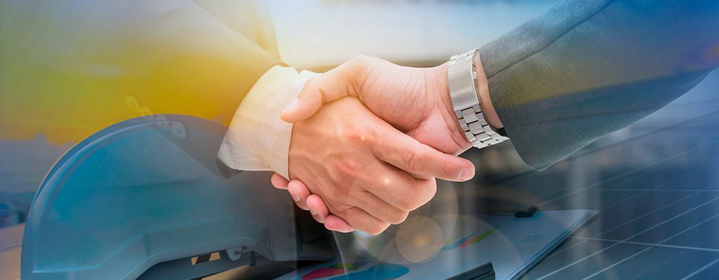 A imagem mostra duas pessoas apertando as mãos, simbolizando parceria e acordo em negócios relacionados a energia solar, evidenciado por painéis solares ao fundo.