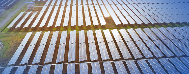 Vista aérea de um grande parque de painéis solares refletindo a luz do sol, mostrando o potencial da energia renovável e sustentável.