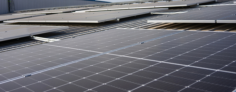 Close de módulos fotovoltaicos instalados em telhado/estrutura, destacando qualidade e padronização do sistema solar.