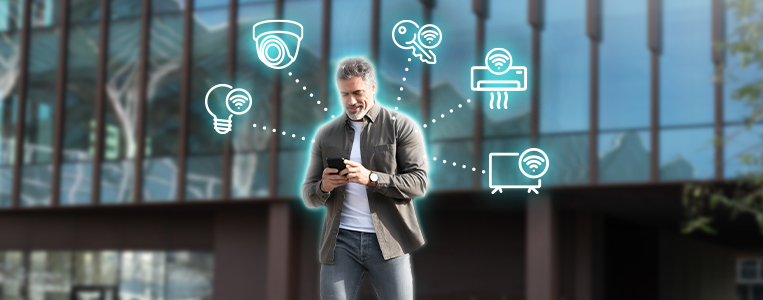 Homem com roupas casuais usando celular em frente a um prédio.