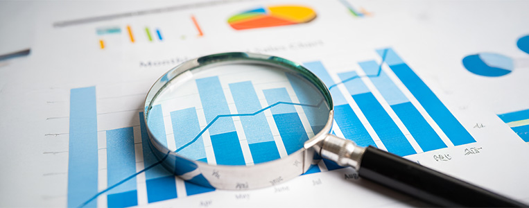 Lupa sobre folha com gráfico.