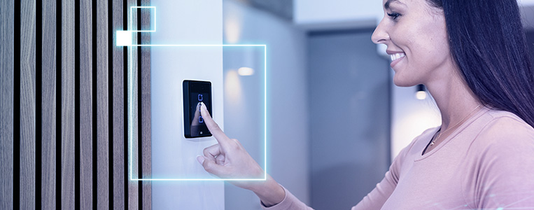 Mulher sorridente usando tecnologia de controle de acesso digital em ambiente moderno, destacando o uso de tecnologia com interface digital de alta tecnologia.