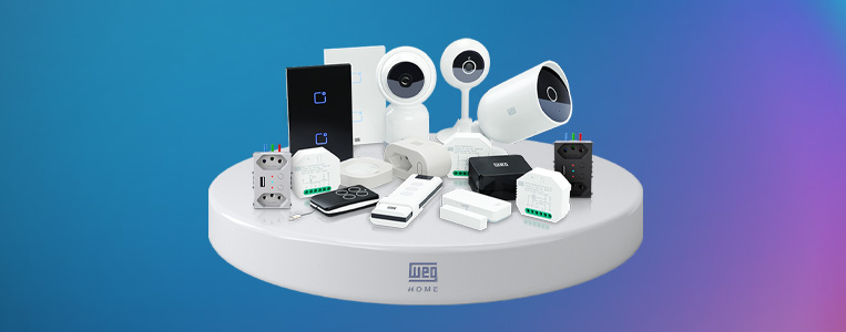 Variedade de dispositivos de segurança e automação doméstica, como câmeras, sensores, alarmes e controles inteligentes, sobre uma bancada branca com fundo azul.