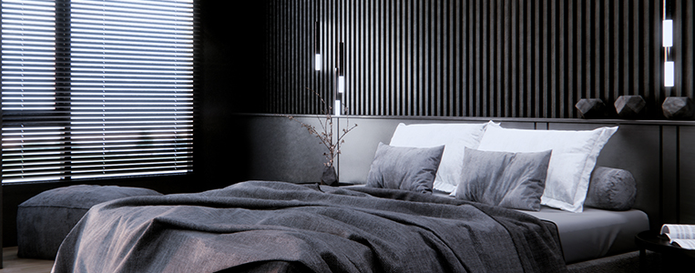 Quarto moderno com cama de roupas cinza, decorado com almofadas, com paredes de madeira escura, iluminação suave e janela com persianas horizontais.