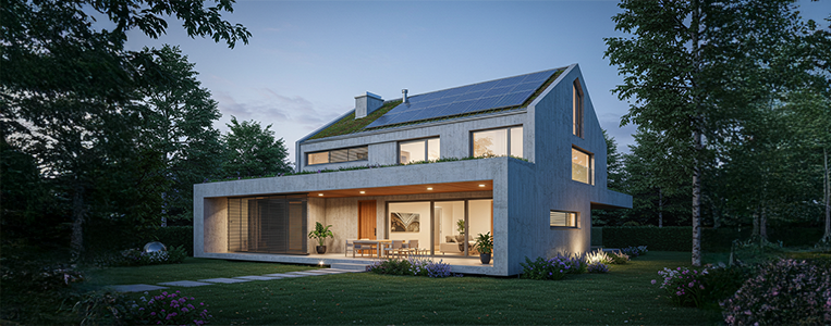 Casa contemporânea ao entardecer, com painéis solares no telhado, jardim ao redor e grandes janelas iluminadas.